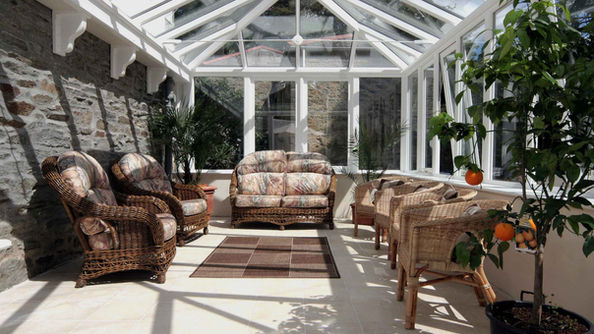 Interior of a traditional hardwood conservatory with glazed roof and wicker furniture