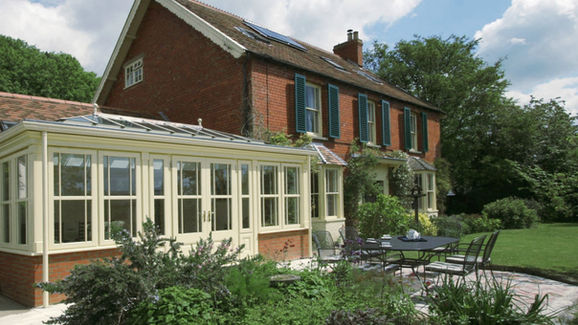 Traditional hardwood orangery with lantern roof and white timber frames on red brick house