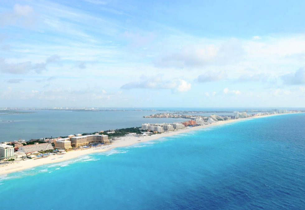Aerial view of Cancún’s Caribbean coastline with white-sand beaches, turquoise water, and beachfront resorts.