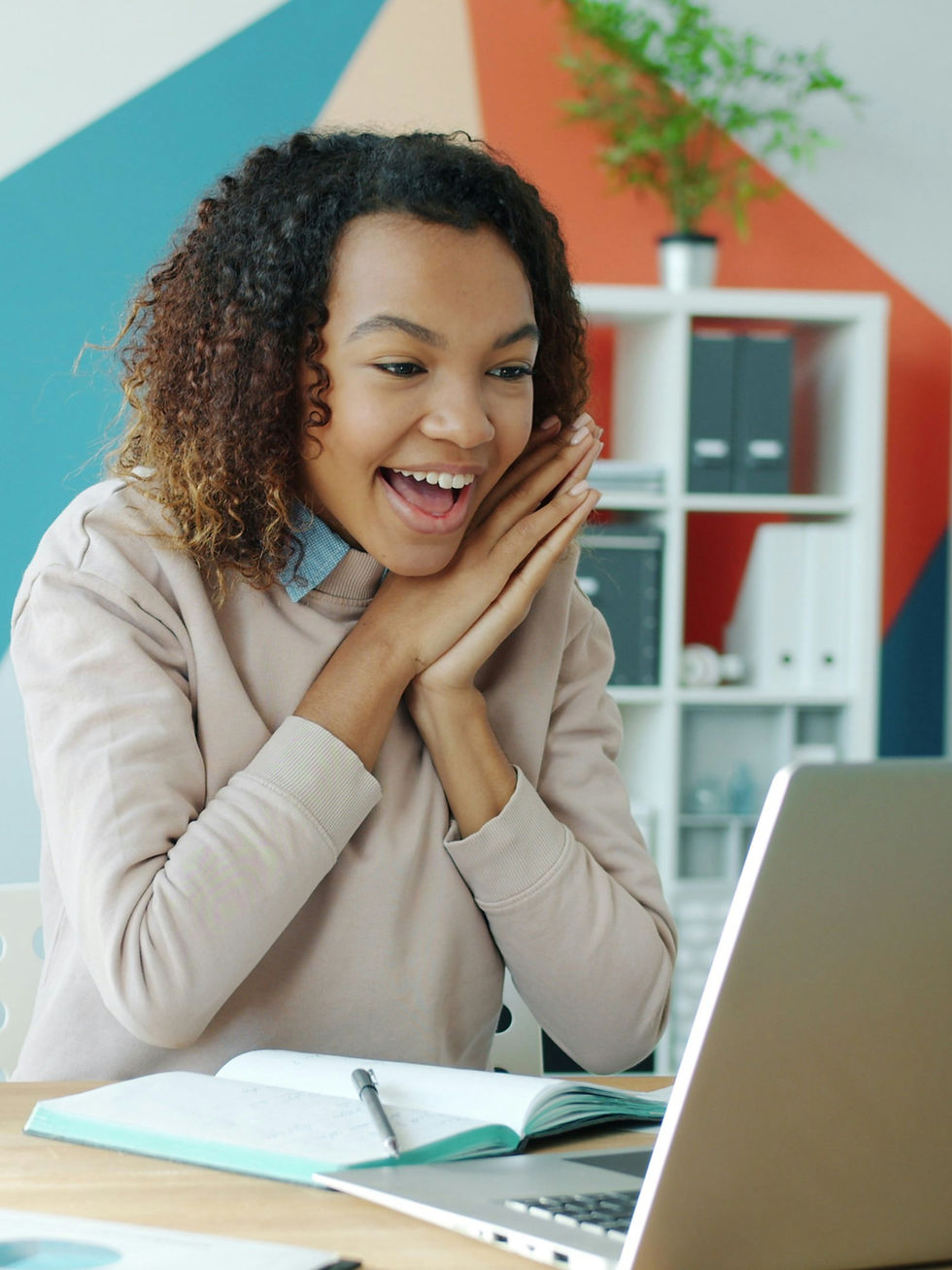 Travel agent smiling while working on laptop, excited about starting a new career from home.