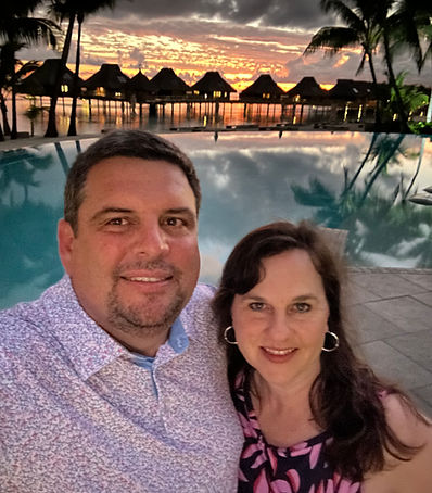 Jodi Wooten and her husband celebrating their anniversary at a tropical resort.