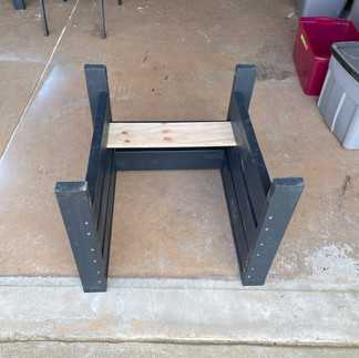 The chair frame is turned upside down to attach the bottom slat to the back.