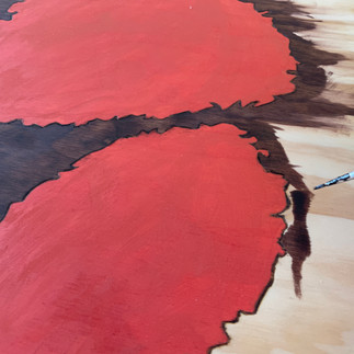 Stain is applied to the desktop outside of the wood burned design using a small brush.