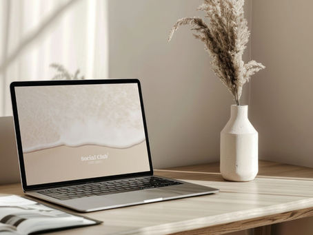 A Table with laptop and white flower vase.