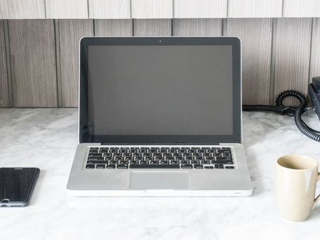 table with laptop, cellphone, telephone and coffee mug.