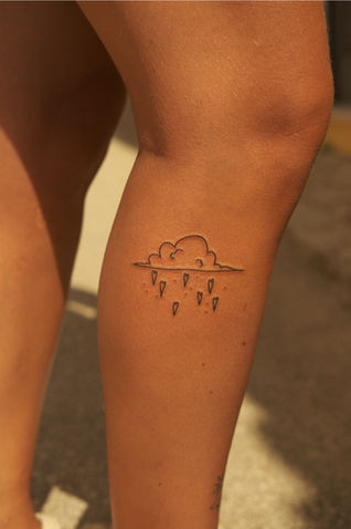 Bold line tattoo of a cloud with raining hearts on leg – playful blackwork by Vangotattoo in Algarve