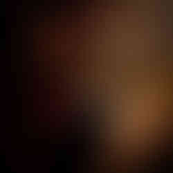 Tattoo artist concentrating deeply while tattooing a client's arm. The artist is wearing a headlamp for precision, and the scene has a warm, intimate ambiance.