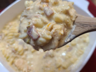 White sauce pasta with bacon and chicken on wooden spoon.