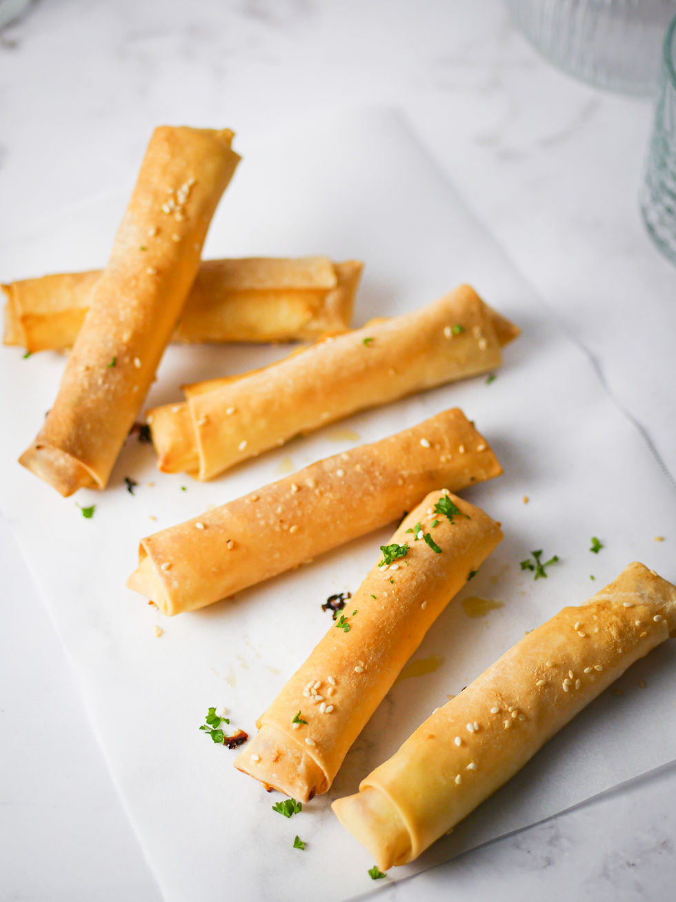 gluten free halloumi, honey and chilli filo cigars on a sheet of white baking paper.
