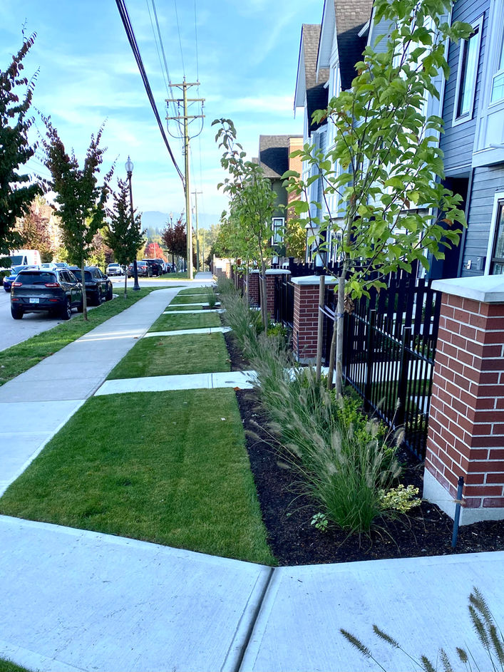 Townhouse with beautiful new landscaping and black fence and rails.