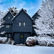 A dark grey house surrounded by snow covered trees