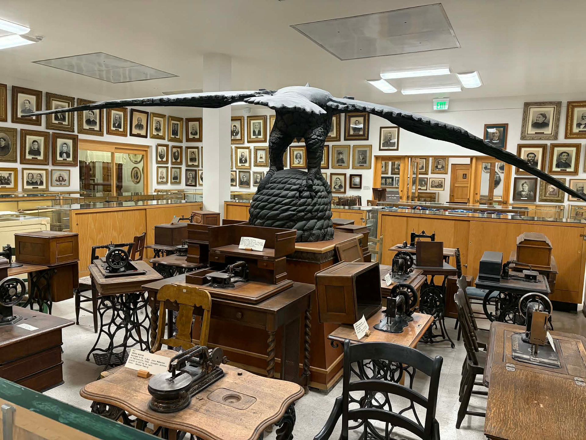 a giant eagle sculpture in a room of antique desks and portraits