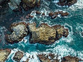 Aerial view of blue ocean waves crashing against rocks