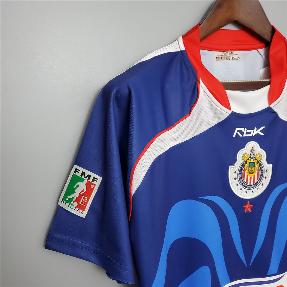Thumbnail: Blue and white Chivas jersey with Reebok logo and emblem on display.