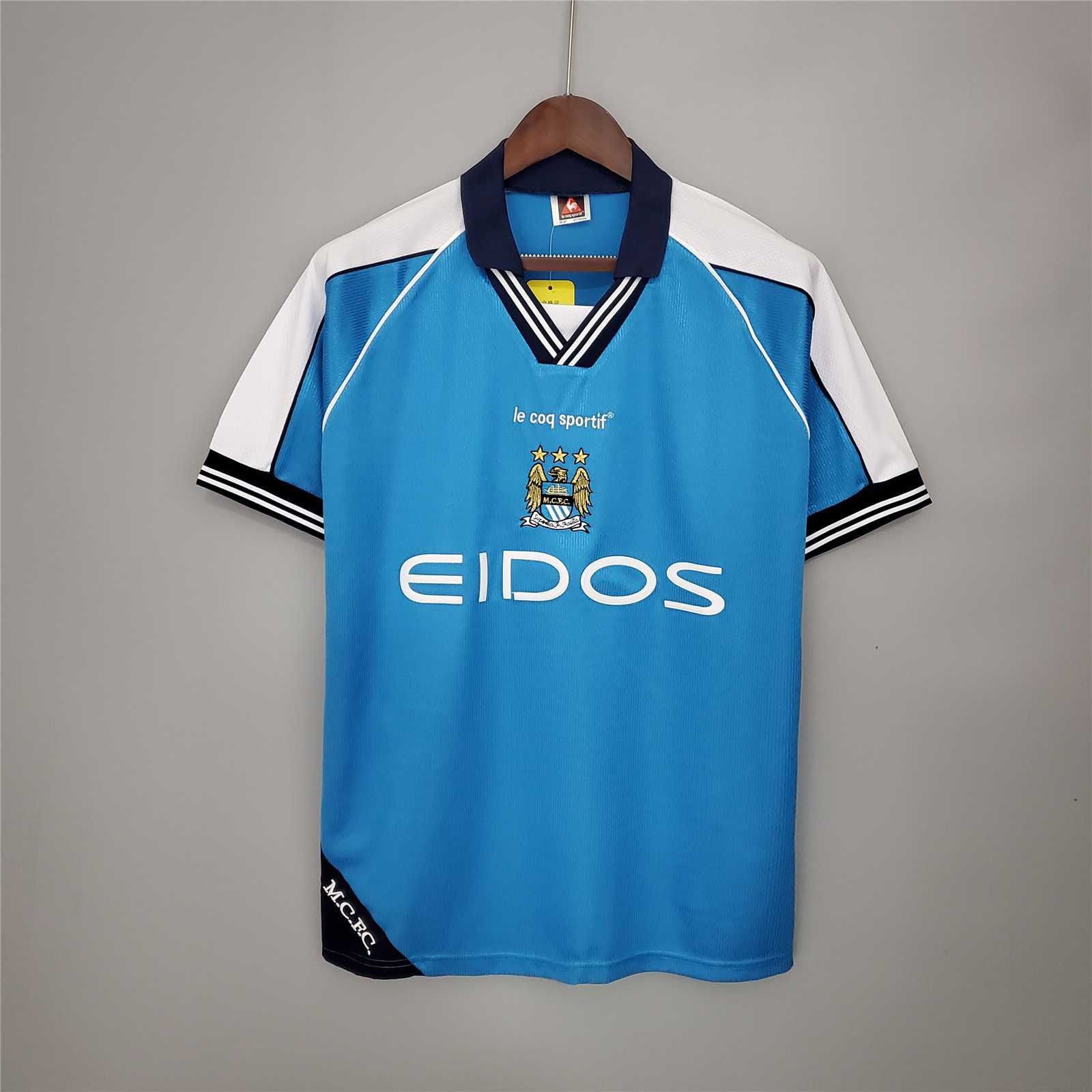 Sky blue Manchester City football kit with EIDOS text and logo displayed.
