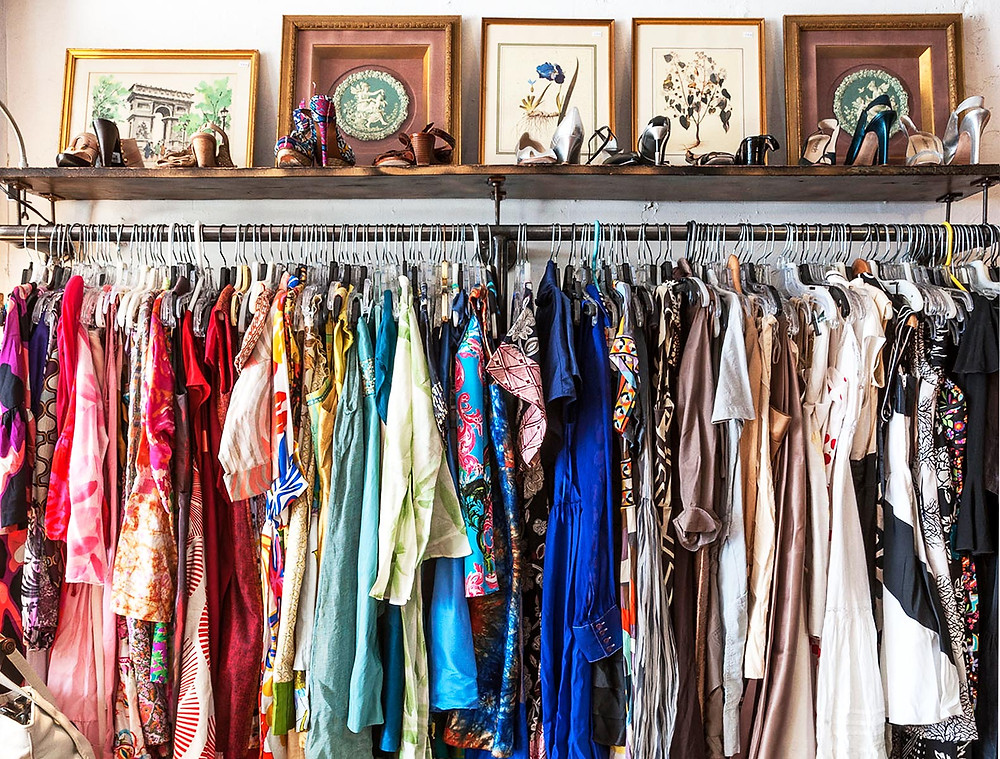 Rack of clothes and shoes from a thrift store.