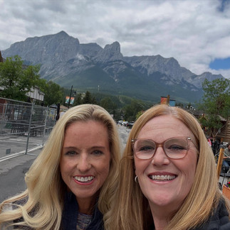 women smiling with the Rocky Mountains in the background during a Kananaskis and Banff getaway.