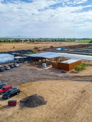 Aerial view of Arizona Worm Farm showing fields, greenhouses, compost areas, and parking lot under a bright sky.