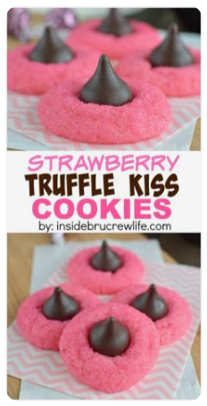 Pink strawberry truffle cookies topped with chocolate kisses arranged on a baking tray