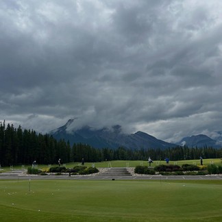 Dramatic cloudy sky over the Rocky Mountains in Kananaskis with forest and open field below.
