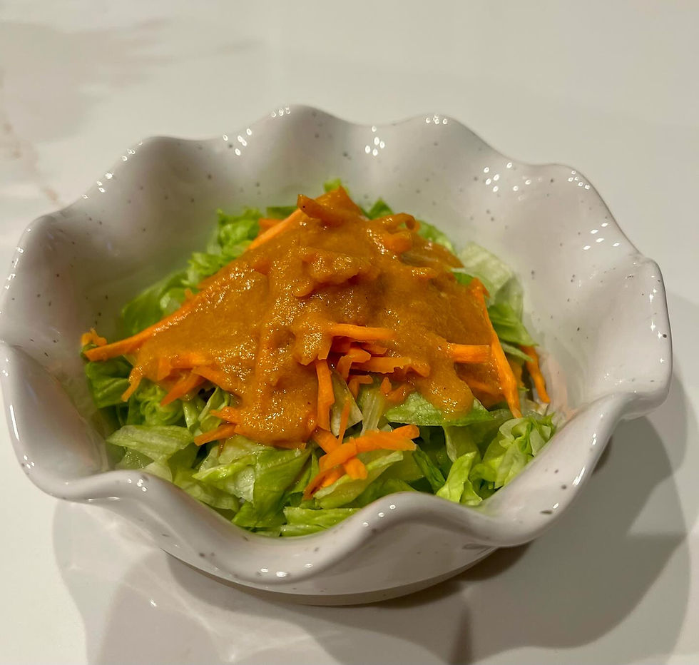 Fresh iceberg lettuce salad topped with homemade Benihana-style ginger dressing, served in a white scalloped bowl.