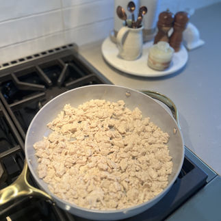 Ground chicken cooking in skillet – Crumbled chicken browning in a skillet on the stovetop.