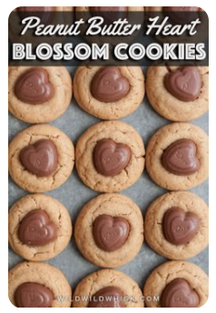 Peanut butter cookies topped with heart-shaped chocolates arranged on a baking sheet