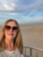 Tammie standing on a balcony overlooking the sandy shoreline and ocean at Virginia Beach’s north end.