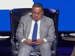 Keith Ellison uses his phone on stage as woman shares emotional story, cries