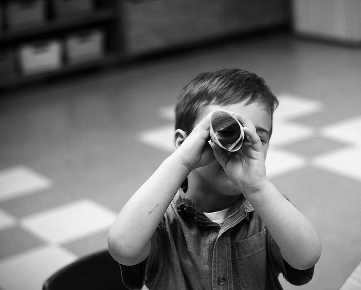 A child looking through a newspaper telescope.