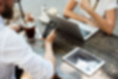 People at table with Macbook, iPhone and iPad