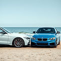 two identical BMWs side by side perched next to each other at the beach.jpg