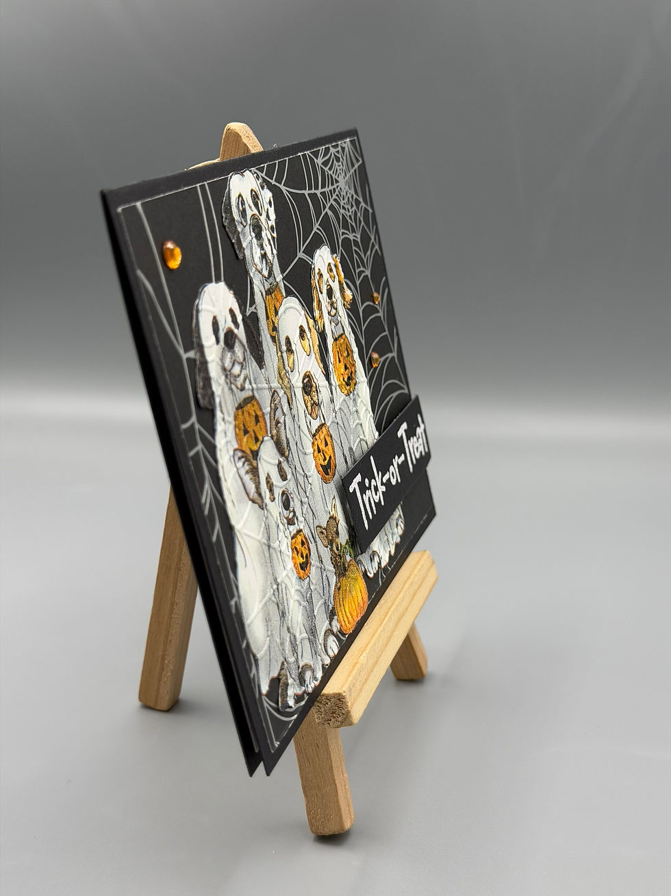 Thumbnail: “Handmade Halloween card featuring dogs in ghost costumes holding jack-o’-lanterns with spiderweb background and ‘Trick-or-Tr