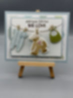 Celebrate the arrival of a new baby with this handcrafted card featuring adorable baby-themed cutouts — a teddy bear, onesie,
