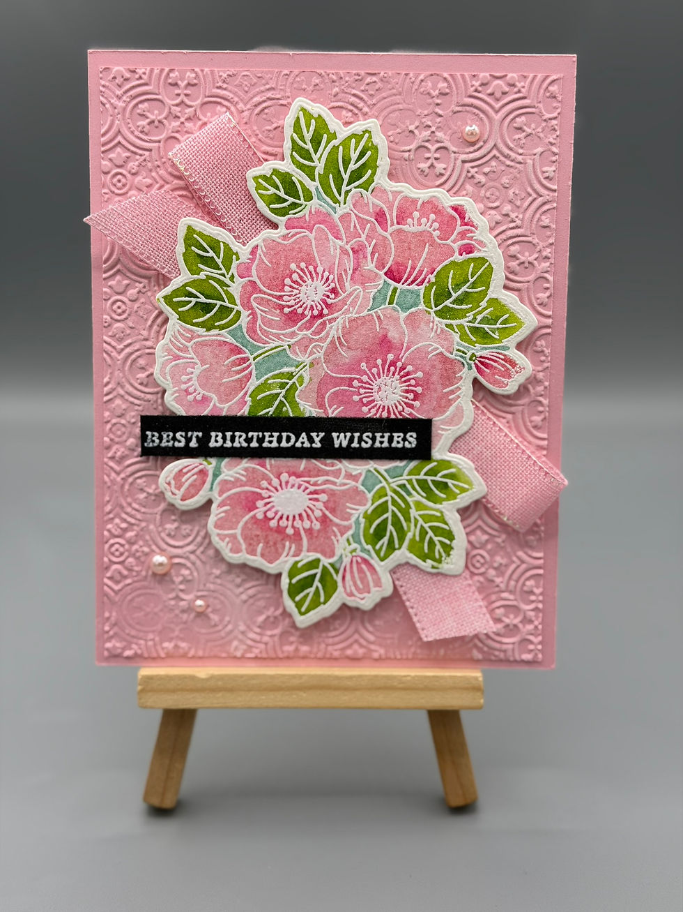 Handmade pink embossed floral birthday card with ribbon and “Best Birthday Wishes” message.