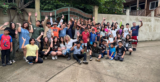 Children and Blue Water Surrender volunteers raising their hands during a mission trip activity