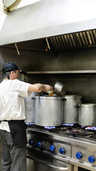 cocinero traspasando caldos de una olla a otra