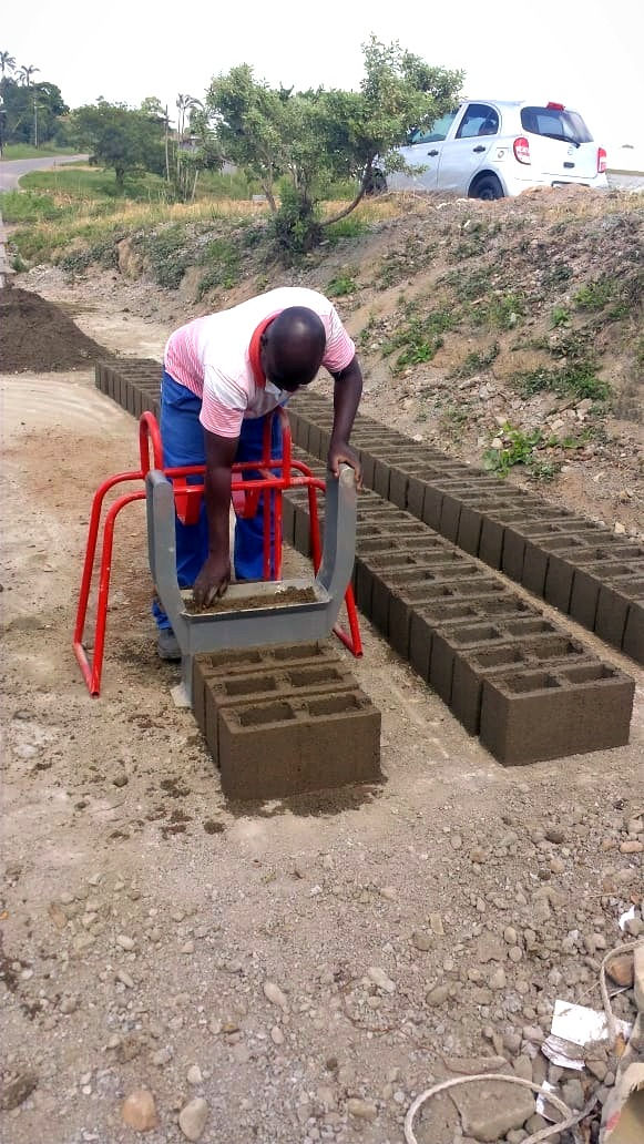 A brick-maker is filling the Doubell hand mould with block mixture to bake M6 cavity blocks