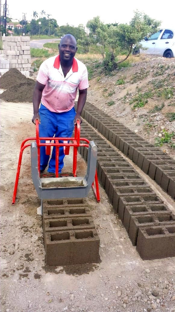 A happy South African man with his Doubell brick machine after making a batch of M6 cavity blocks in his brickyard