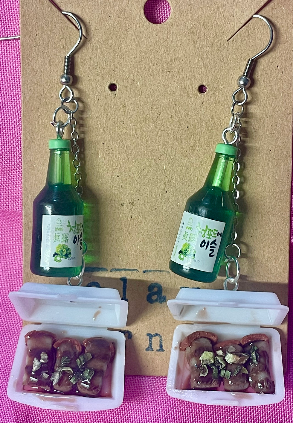 dangle earrings of Japanese braised pork belly with scallions in a white takeout container and a sake bottle
