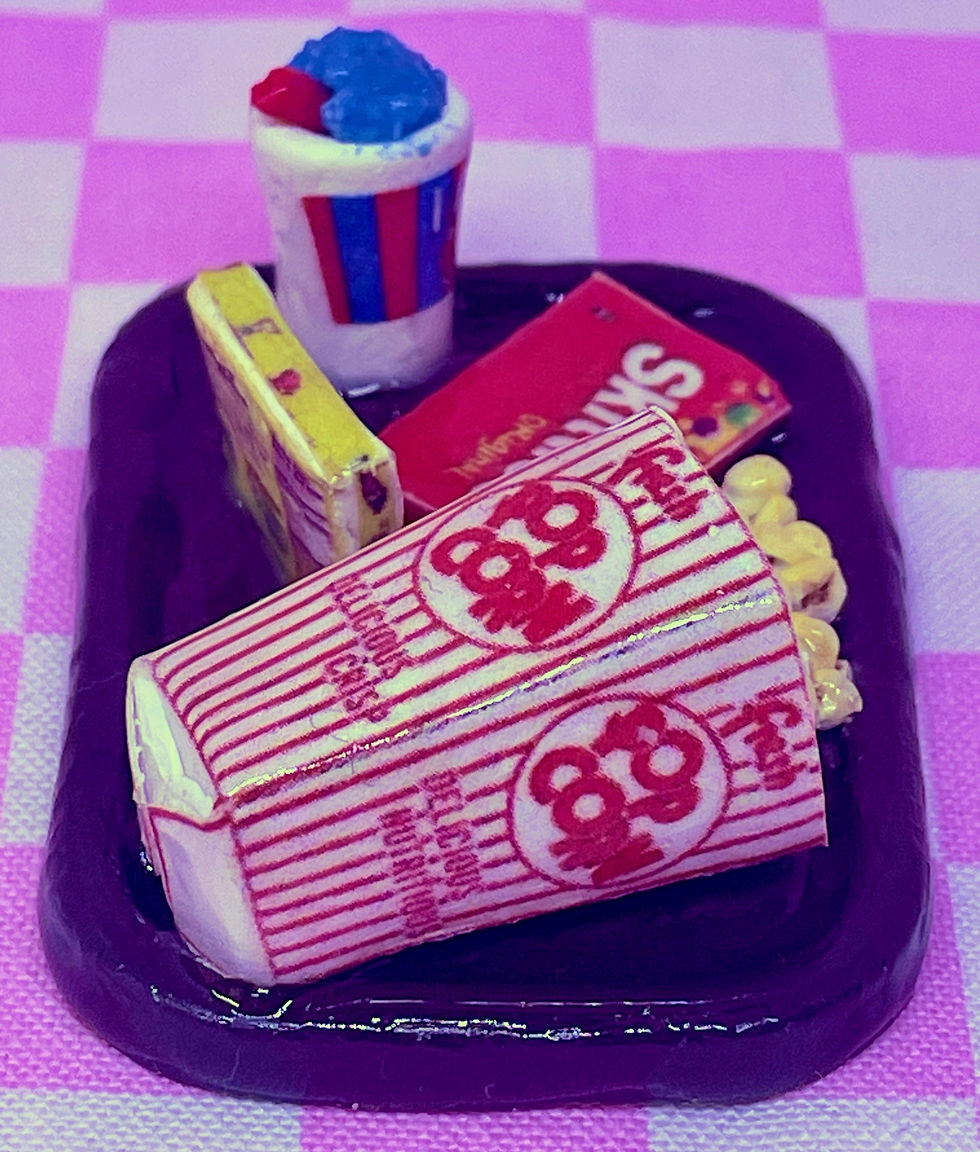 fridge magnet of movie theatre snacks on a brown tray with spilled popcorn from a popcorn bucket a box of skittles candy a bo