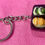 Thumbnail: keychain of a black bento box with edamame and 2 sushi rolls and a shrimp sashimi