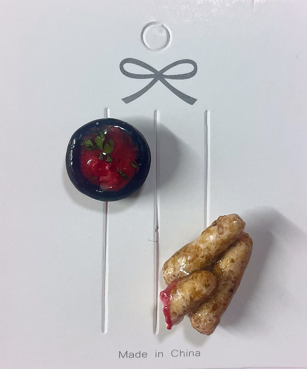lapel pins of 3 mozzarella sticks , one half eaten and dipped in marina sauce and a pin of marinara sauce in a black dish