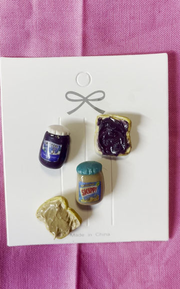 Thumbnail: lapel pins of a smuckers grape jelly jar and a skippy peanut butter jar and slices of bread with peanut butter and jelly