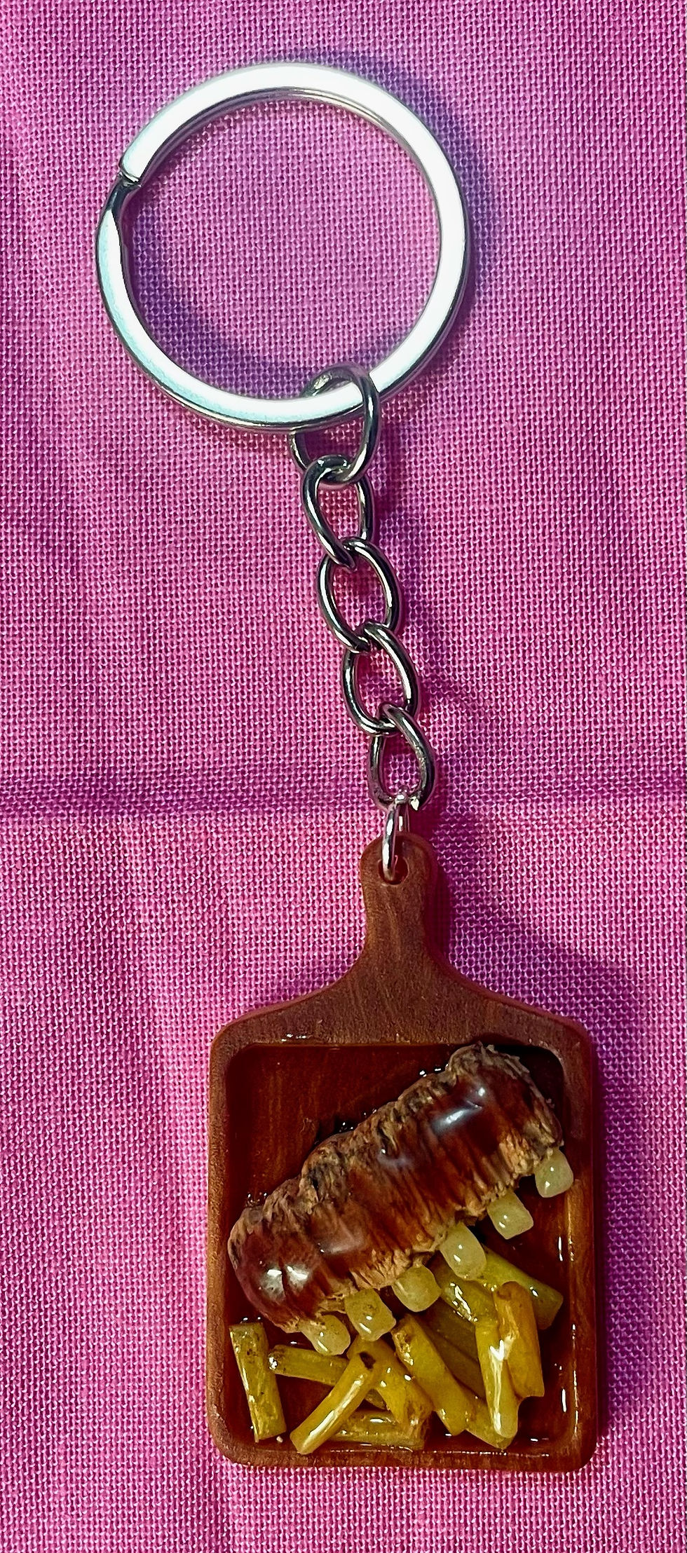 keychain of bbq ribs and french fries on a rectangle wooden cutting board