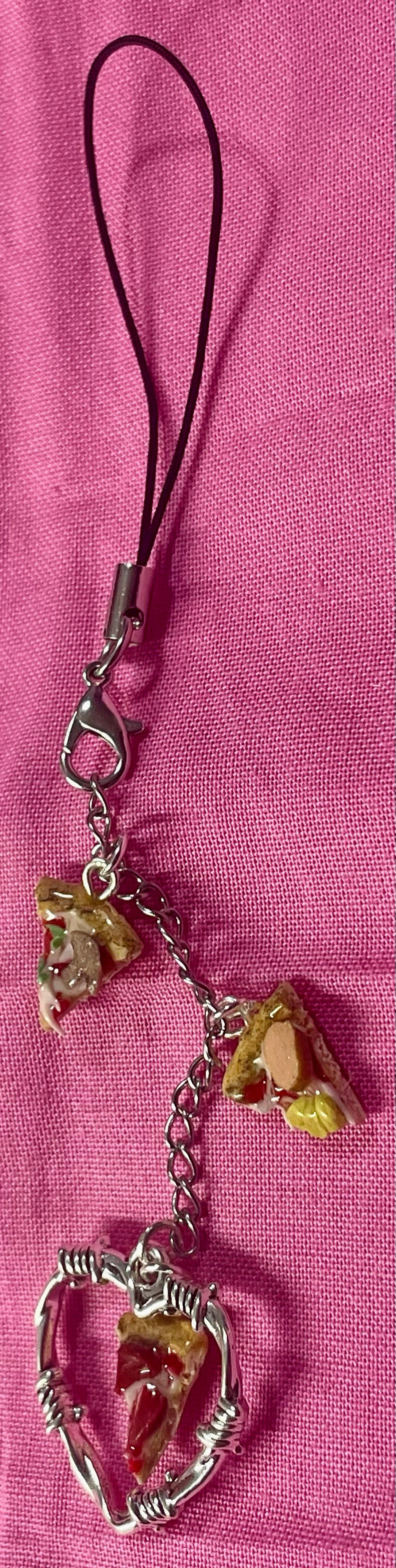 Thumbnail: phone charm of a slice of pepperoni pizza inside of a barbed wire heart with a hawaiian pizza slice and mushroom pepper slice
