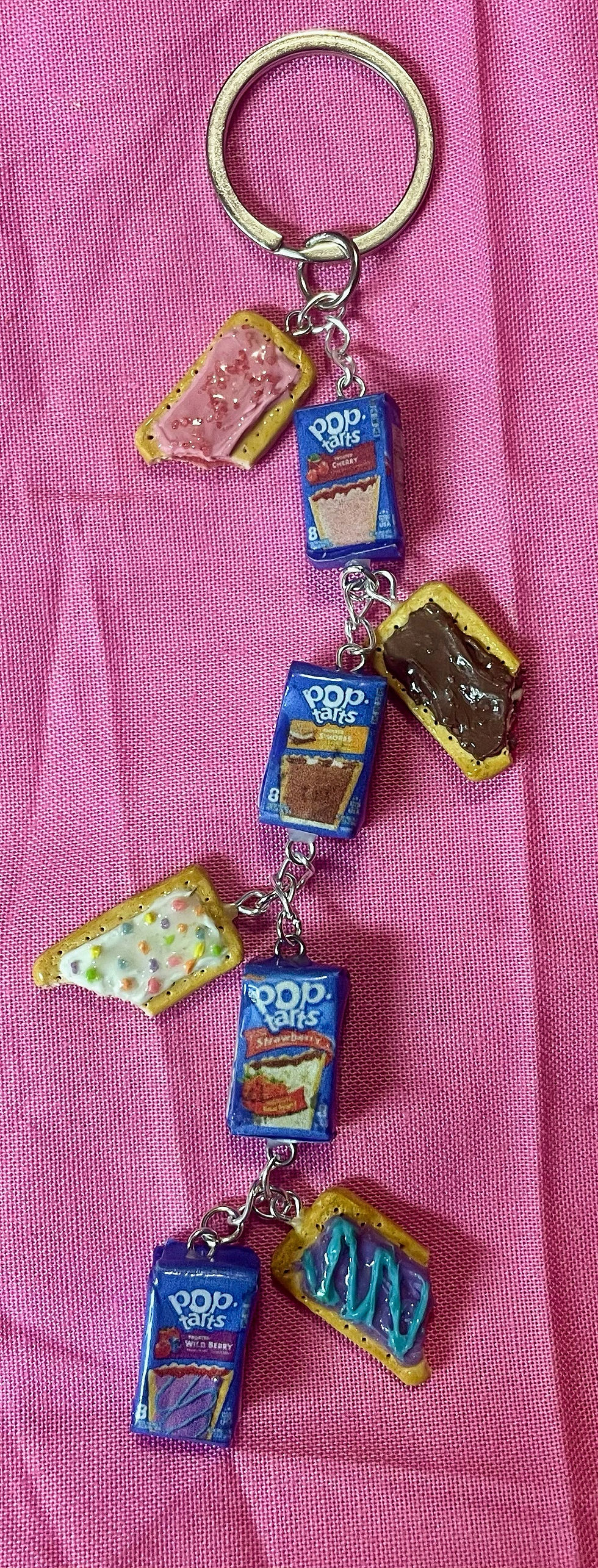 keychain of 4 pop tarts including blue wild berry, cherry, strawberry and smores poptart, all pop tarts have a bite mark