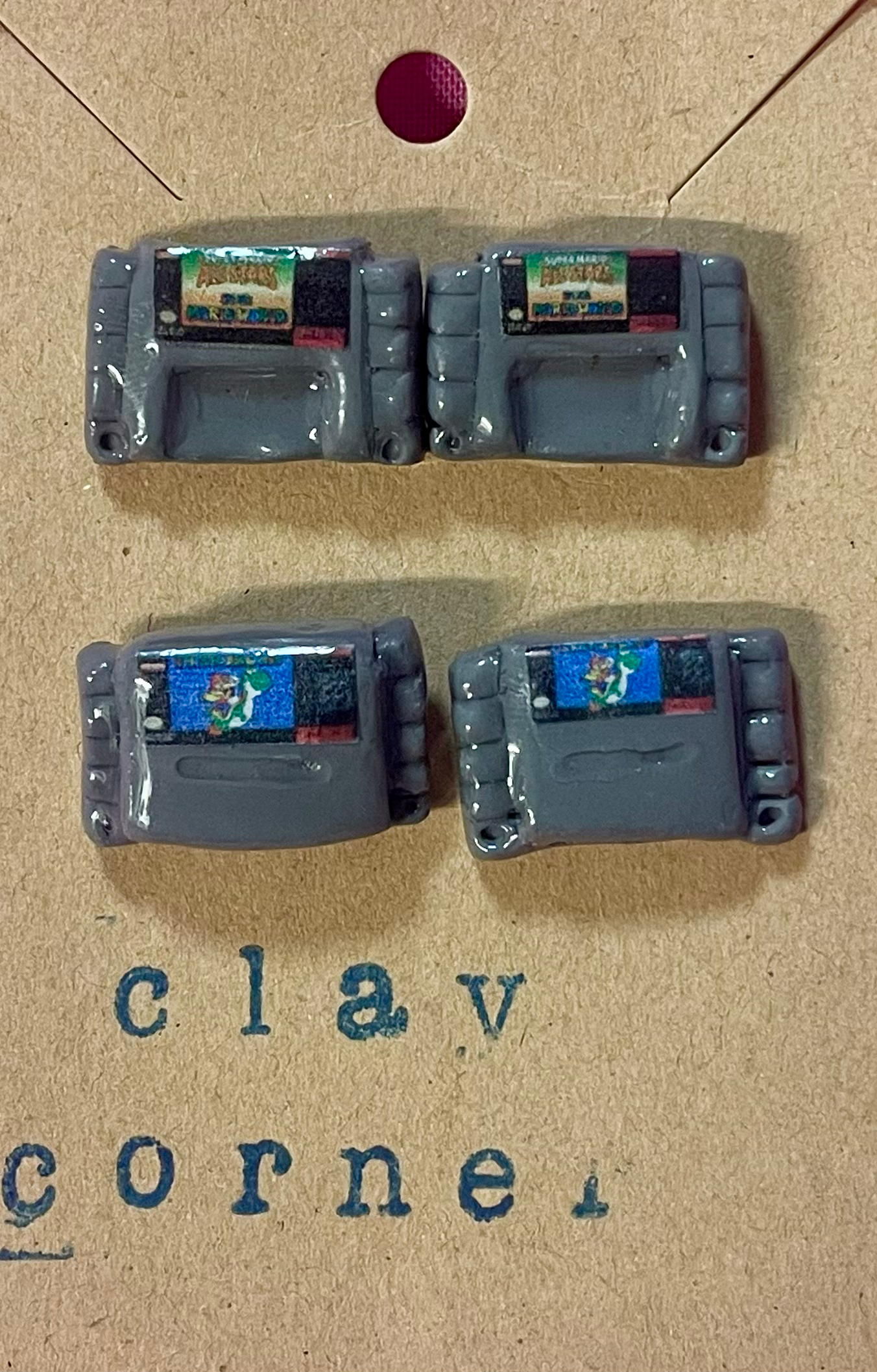 Two pairs of stud earrings of super nintendo snes game cartridge of mario all stars and super mario