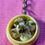 Thumbnail: keychain of soup dumplings in bamboo steamers with soy sauce and scallions and a dumpling with a bite taken