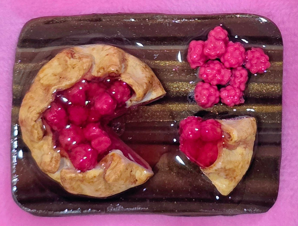 Close-up of a miniature raspberry pie food magnet showing realistic baked crust texture and glossy raspberry detail